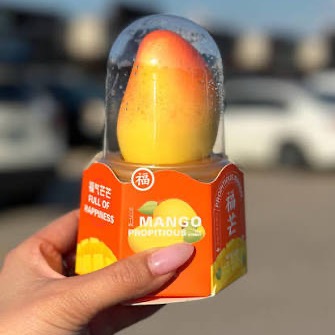 Mango shaped ice cream in a clear dome cup on an orange box