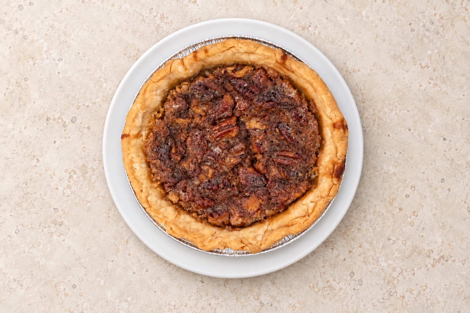 Mini pecan pie in a foil tin on a white plate